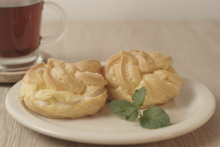 Kue Soes or choux Ã  la crÃ¨me on white plate. Perfectly puffed and filled with a creamy filling, this classic French dessert is sure to delight. Selective Focus , Closeupの写真素材