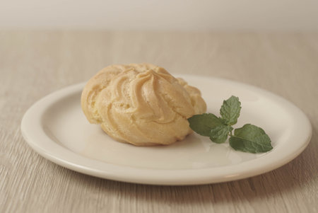 Kue Soes or choux Ã  la crÃ¨me on white plate. Perfectly puffed and filled with a creamy filling, this classic French dessert is sure to delight. Selective Focus , Closeupの写真素材