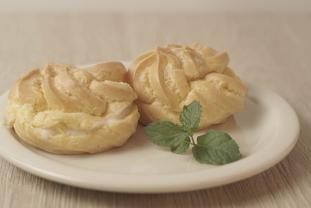 Kue Soes or choux Ã  la crÃ¨me isolated on white plate. Perfectly puffed and filled with a creamy filling, this classic French dessert is sure to delight. Selective Focus , Closeupの写真素材