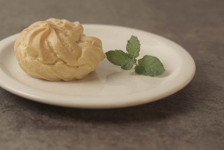 Kue Soes or choux Ã  la crÃ¨me on white plate. Perfectly puffed and filled with a creamy filling, this classic French dessert is sure to delight. Selective Focus , Closeupの写真素材