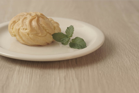 Kue Soes or choux Ã  la crÃ¨me on white plate. Perfectly puffed and filled with a creamy filling, this classic French dessert is sure to delight. Selective Focus , Closeupの写真素材