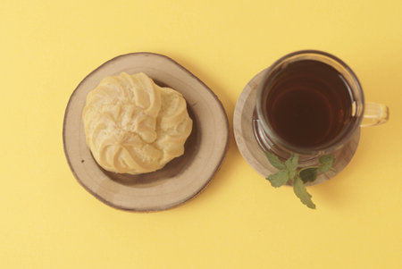 Kue Soes or choux Ã  la crÃ¨me isolated on a yellow background. Perfectly puffed and filled with a creamy filling, this classic French dessert is sure to delight. Selective Focus , Closeupの写真素材