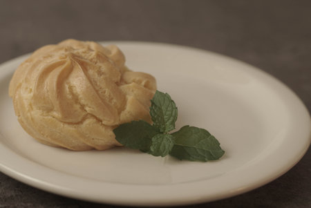 Kue Soes or choux Ã  la crÃ¨me on white plate. Perfectly puffed and filled with a creamy filling, this classic French dessert is sure to delight. Selective Focus , Closeupの写真素材