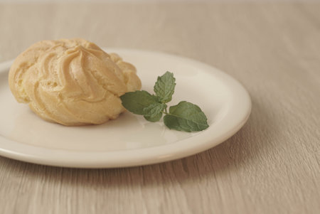 Kue Soes or choux Ã  la crÃ¨me on white plate. Perfectly puffed and filled with a creamy filling, this classic French dessert is sure to delight. Selective Focus , Closeupの写真素材