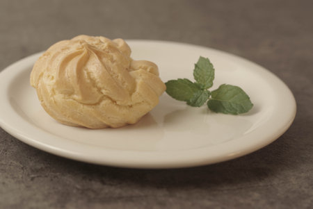 Kue Soes or choux Ã  la crÃ¨me on white plate. Perfectly puffed and filled with a creamy filling, this classic French dessert is sure to delight. Selective Focus , Closeupの写真素材