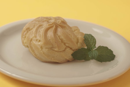 Kue Soes or choux Ã  la crÃ¨me isolated on a yellow background. Perfectly puffed and filled with a creamy filling, this classic French dessert is sure to delight. Selective Focus , Closeupの写真素材