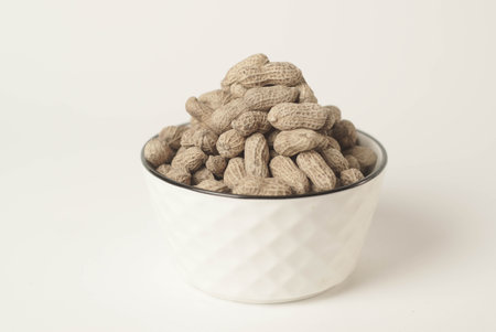 This high-quality image showcases perfectly roasted peanuts isolated on a clean white background,...