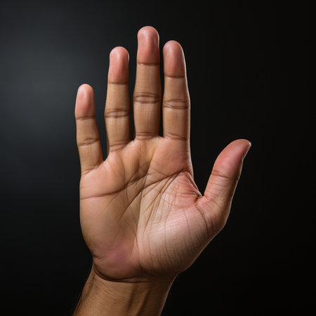 Man's hand showing stop gesture on black background, close-upの素材