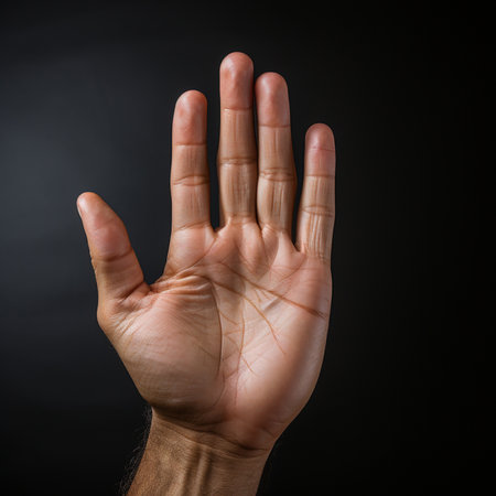 Man's hand showing stop gesture on black background with copy space.の素材
