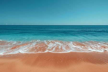 A tranquil tropical beach with fine sand and clear turquoise water meeting the shore under a vast, cloudless blue sky.の素材