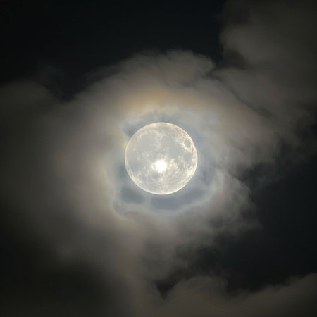 Full moon in the dark night sky with clouds and bright sun.の素材