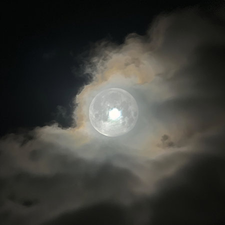 The full moon in the night sky with clouds and the sun.の素材
