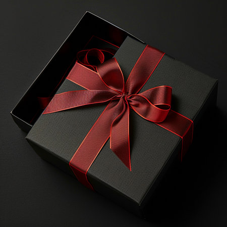 Black gift box with red ribbon on black background. Top view.の素材