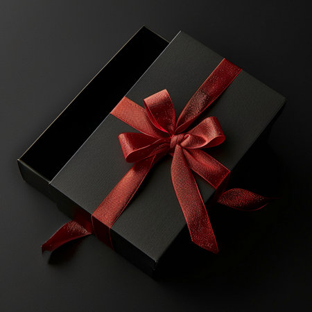 Black gift box with red ribbon on black background. Top view.の素材