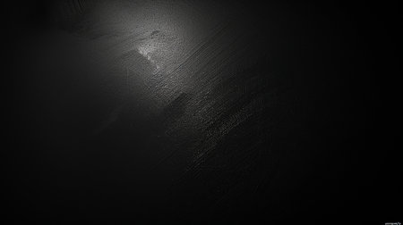 A dark, textured background with a soft light source creating a subtle glare and visible linear patterns, suggesting depth and material.の素材