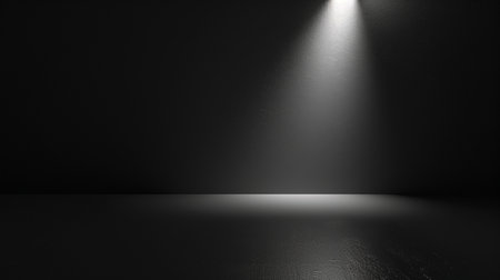 A dark, empty studio with a textured wall and floor, illuminated by a single spotlight creating dramatic shadows. Ideal for minimalist presentations.の素材
