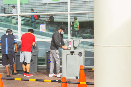 Lima, Peru - April 8 2020: People rubbing hand sanitizer on their hands in a queue for a supermarket. Policies of social distancing amid coronavirus outbreak in South America.のeditorial素材