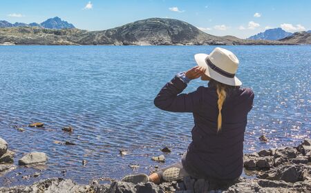 Beautiful woman sitting on the shore of the lake in front of the Pastoruri glacier, in the Huascaran National Park, Huaraz / Peru.の写真素材
