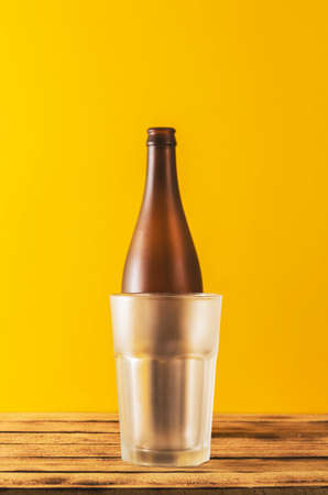 Empty beer glass, bottle beer on a wooden background and yellow, selective focus.の写真素材
