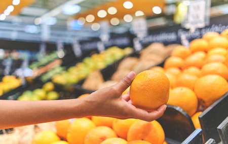 Young Woman Choosing Oranges in Grocery Store. Concept of healthy food, bio, vegetarian, diet. Selective focus.の写真素材