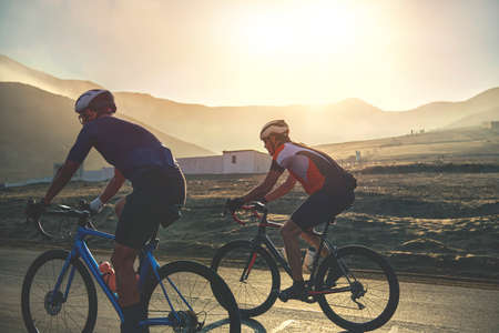 Group of cyclist friends riding race bike on sunset highway, sunset bike competitionの写真素材