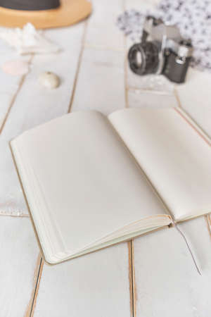 Top view of an analog camera and a notebook on a wooden table, photographer's hands hold old film camera on wooden background, travel outfit, concept travelの写真素材