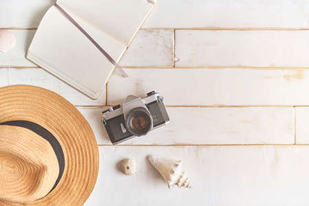 Top view of an analog camera and a notebook on a wooden table, photographer's hands hold old film camera on wooden background, travel outfit, concept travelの写真素材