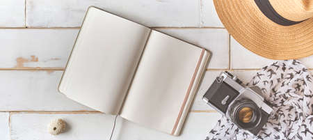 Top view of an analog camera and a notebook on a wooden table, photographer's hands hold old film camera on wooden background, travel outfit, concept travelの写真素材