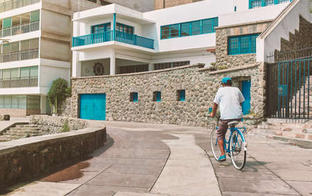 Man riding a bicycle near the beach on the boulevard by the pier in Ancon, Peru, sunny day. New normal conceptの写真素材