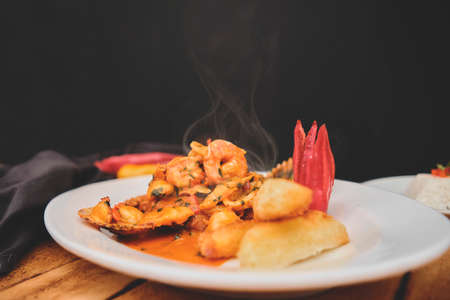 Peruvian food: Peruvian Dish a lo macho fish, wooden table, served on a white plate, (Fish fried in seafood sauce, accompanied by potato sea bream and rice)の写真素材