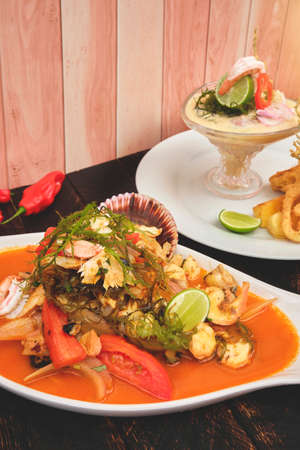 Peruvian food: called "Leche de tigre" and "sudado de seafood", seafood (fish sweat, scallops, shrimp, octopus, snail, mixed with vegetables and spicy juice) top view. Selective focusの写真素材