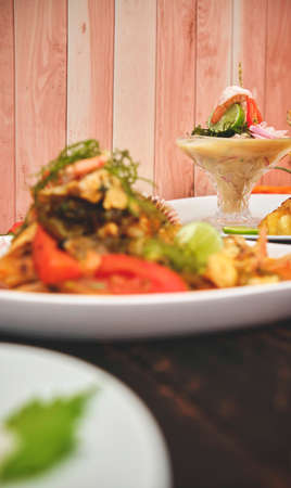 Peruvian food: called "Leche de tigre" and "sudado de seafood", seafood (fish sweat, scallops, shrimp, octopus, snail, mixed with vegetables and spicy juice) top view. Selective focusの写真素材