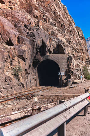 Beautiful shot of train rails surrounded by nature leading to the dark tunnel Link Ã Title: Beautiful shot of train rails surrounded by nature leading to the dark tunnelの写真素材