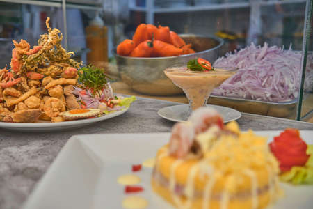 Peruvian food: chicharron de pez or fish cracklings with fried cassava and onion salad with chili, served on a white plate. Selective focusの写真素材