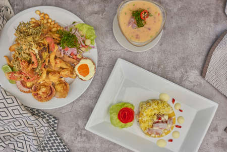 Peruvian food: chicharron de pez or fish cracklings with fried cassava and onion salad with chili, served on a white plate. Selective focusの写真素材