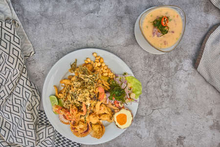 Peruvian food: chicharron de pez or fish cracklings with fried cassava and onion salad with chili, served on a white plate. Selective focusの写真素材