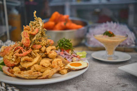 Peruvian food: chicharron de pez or fish cracklings with fried cassava and onion salad with chili, served on a white plate. Selective focusの写真素材