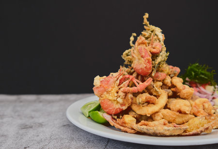 Peruvian food: chicharron de pez or fish cracklings with fried cassava and onion salad with chili, served on a white plate. Selective focusの写真素材