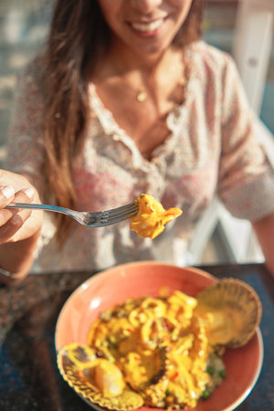 Beautiful young girl tasting a delicious rice with seafood, peruvian food called "arroz con marino"の写真素材