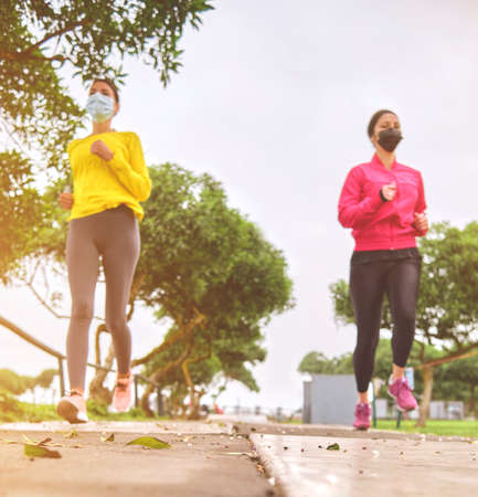 Multiethnic women jogging on the street, jogging in city in duskの写真素材
