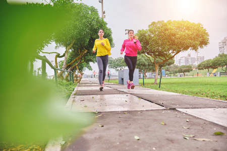 Multiethnic women jogging on the street, jogging in city in duskの写真素材