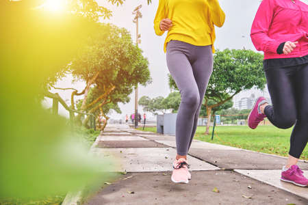 Multiethnic women jogging on the street, jogging in city in duskの写真素材