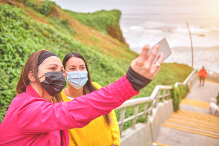 Two young athletic women taking a picture after running in a park - Best friends training together outdoors, Sport lifestyle conceptの写真素材