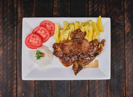 Delicious and succulent Beef steak meat with accompaniments: French fries, tomato and rice.の写真素材