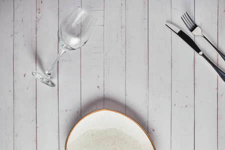 Empty plates, forks and glass of wine on white wood background. Top view. Concept mockup