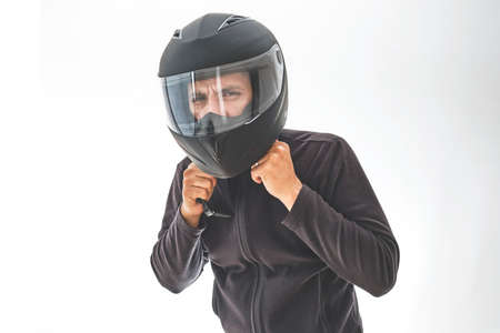 Man with a motorcycle helmet giving a thumbs up gesture. Isolated on white studio wall.の写真素材