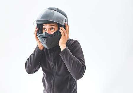 Man with a motorcycle helmet giving a thumbs up gesture. Isolated on white studio wall.の写真素材