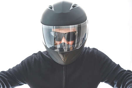 Portrait of guy with black checkered jacket and motorcycle helmet pretending to ride motorcycle,...