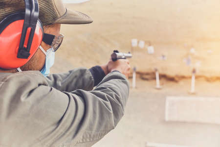 Man with hand gun aiming at shooting range and releasing stress. Selective Focusの写真素材