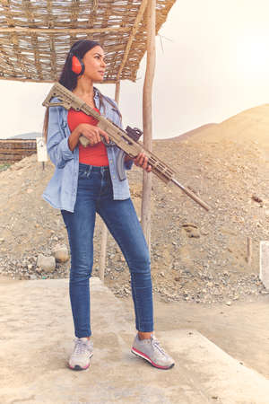 Woman empowered shooter aiming assault rifle at target. Selective Focusの写真素材